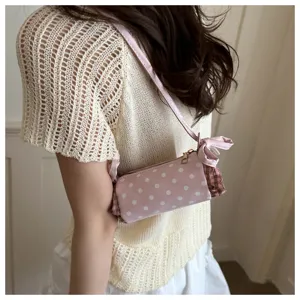 Dettaglio di una borsa a spalla cilindrica rosa a pois in stile coreano con grazioso fiocco.