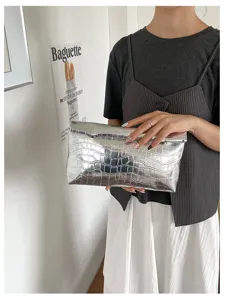 Silver metallic croc-embossed clutch bag detail showing texture, stylish accessory for women.