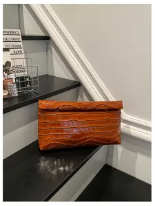Brown crocodile pattern clutch bag detail shot showcasing exquisite texture and design.
