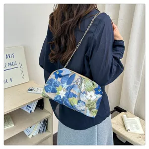 Vue de détail d'un élégant sac bandoulière bleu brodé de fleurs avec chaîne dorée.