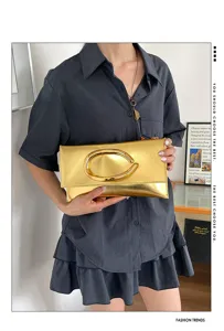 Details van de stijlvolle gouden clutch met unieke metalen handgreep, elegant avondaccessoire.