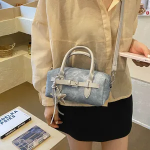 Detalle de bolso de mano Boston casual chic con acabado desgastado y dije de estrella.