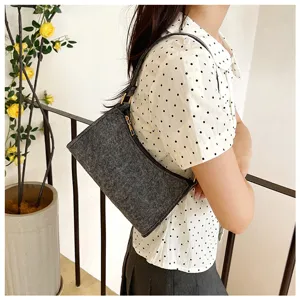 Detailaufnahme einer dunkelgrauen Filz-Schultertasche, modernes minimalistisches Design.