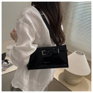 Detail shot of black patent leather underarm bag with chic buckle strap and shiny silver hardware.
