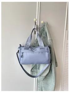 Vista detallada del bolso de hombro cilíndrico casual azul claro con correas cómodas.