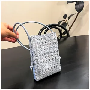 Détail de mini sac bandoulière en cuir tissé bleu clair, sac de téléphone évidé élégant.