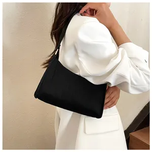 Detailaufnahme einer stilvollen schwarzen Schultertasche am Modell, die modernes Modedesign zeigt.