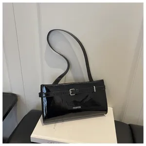 Detailed view of the black glossy patent leather shoulder bag with a chic front decorative buckle.