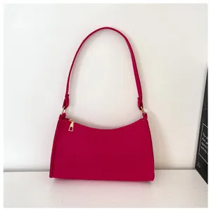 Detailansicht der pinken Schultertasche unter dem Arm mit goldenen Beschlägen und Reißverschluss.