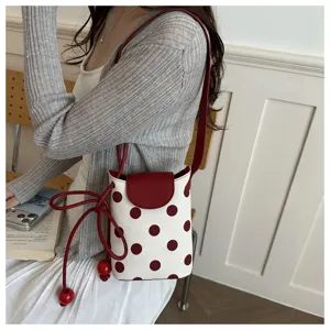 Primo piano di una borsa a secchiello a pois retro con patta rossa e perline di legno.