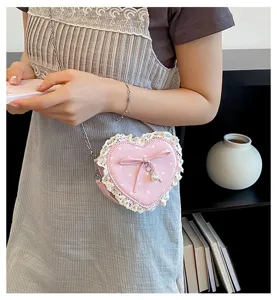 Joli sac bandoulière en dentelle en forme de cœur rose à pois avec nœud et perle.
