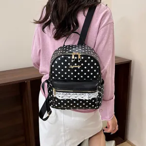 Detail shot of black and white polka dot women backpack with lace trim and golden hardware.
