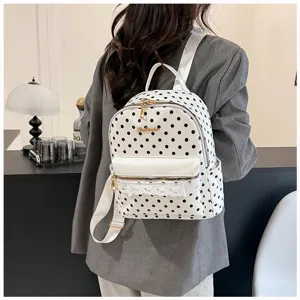 Detail view of the elegant white polka dot backpack featuring cute lace trim and shiny gold zippers.