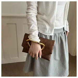 Elegante braune Leder-Clutch Tasche mit markantem goldenen Metallgriff für Damen Mode Detail.
