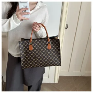 Dettaglio della elegante borsa shopper marrone con motivo monogramma e manici chic.