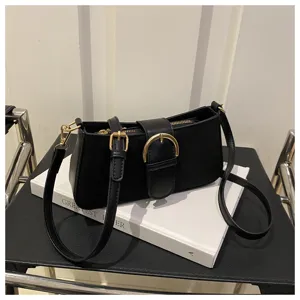 Vista dettagliata di una chic borsa a tracolla nera con fibbia in metallo su libro bianco.