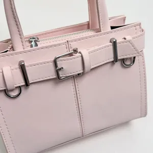 Dettaglio borsa a mano rosa con elegante fibbia a cintura e dettagli in metallo di alta qualità.