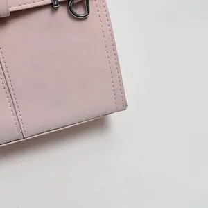 Dettaglio in primo piano della borsa rosa con cuciture fini e fibbia ad anello metallico.