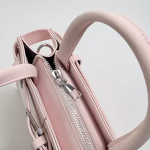 Vista dettagliata della borsa in pelle rosa con cerniera e manico elegante e pratico.
