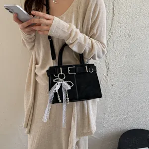 Borsa a tracolla nera da donna con fibbia e ciondolo di perle in pizzo bianco dettagliata.