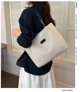 Detailansicht der stilvollen geflochtenen Strohtasche mit Schultergurt fuer Sommer.