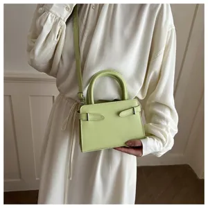 Detail view of a chic light green crossbody handbag featuring stylish side buckle straps.