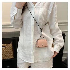 Detailopname van een schattig mini roze tasje met zwarte band gedragen door model.