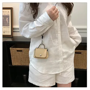 Detail van mini beige leren crossbody tas gedragen door model, trendy accessoire.