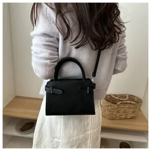 Minimalist black crossbody bag for women, stylish small square purse with top handle and strap.