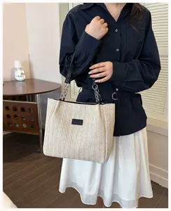 Detailansicht der Strohgewebe-Tasche mit Kettengriffen und einem schicken Sommerlook.