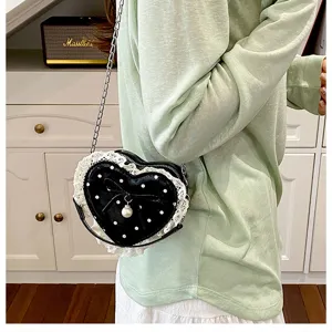 Close-up detail of sweet heart shoulder bag with black polka dots, lace and pearl accent.