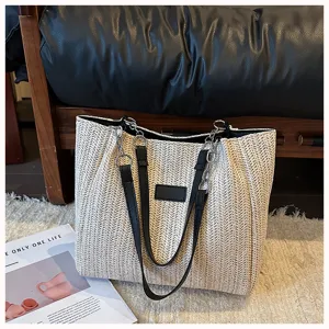 Detailansicht der stylischen Strohtasche mit Lederriemen und Kettendetails.