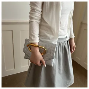 Elegante Clutch Detailansicht mit Metallgriff, schicke graue Ledertasche mit goldenem Ring.