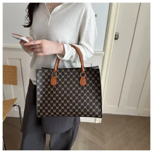 Vista dettagliata del manico e della trama della borsa tote monogram marrone da donna.