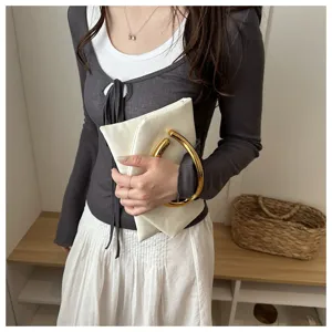 Detailansicht der stilvollen weißen Clutch-Tasche mit edlem großem goldenen Ringgriff.