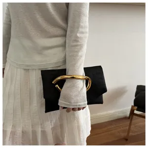 Detailaufnahme einer schwarzen Damen-Clutch mit einzigartigem goldenen Metallgriff, schick.