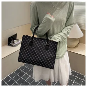 Vista dettagliata di un'elegante borsa shopper nera con motivo monogram in stile.