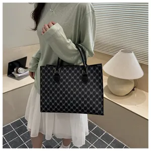 Vista dettagliata della borsa tote nera elegante con stampa a lettere nella stanza.