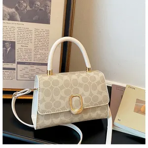Detailansicht einer schicken hellen Handtasche mit monogrammiertem Muster und weißem Griff.
