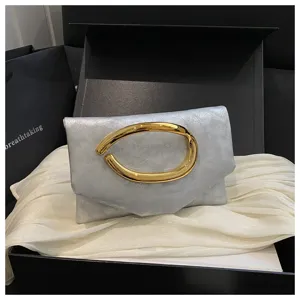 Nahaufnahme der silbernen Clutch mit auffälligem goldenen Griff in schwarzer Geschenkbox