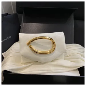 Elegante weiße Clutch Tasche mit markantem goldenen Metallgriff für stilvolle Damenoutfits.