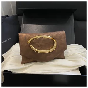 Nahaufnahme einer stilvollen bronzefarbenen Clutch mit einzigartigem goldenen ovalen Metallgriff.