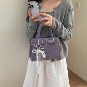 Vista di dettaglio della borsa a mano viola con fibbia e ciondolo a fiocco donna.