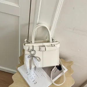 Primo piano di una chic borsa da donna beige con fibbia decorativa e ciondolo di perle in pizzo.