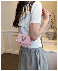 Détails du sac bandoulière rose pailleté avec chaîne et logo V en métal, style d'été chic.