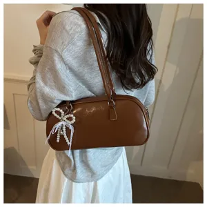 Gros plan détail du sac porté épaule élégant en cuir PU marron avec nœud perlé.