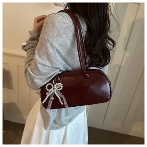 Vue détaillée du sac porté épaule minimaliste rouge foncé avec un nœud en perles dentelle.