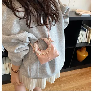 Detail view of a trendy pink crescent shoulder bag with cute lace trim and metal ring accent.
