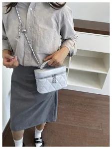 Vue détail du sac bandoulière matelassé avec bandoulière chaîne et charms boule métallique.