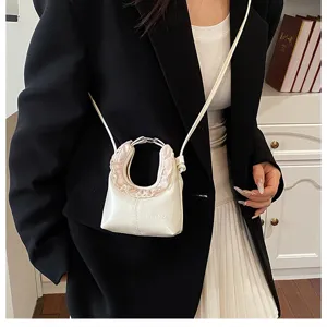 Chic mini white crescent crossbody bag with ruffled handle design for stylish women.